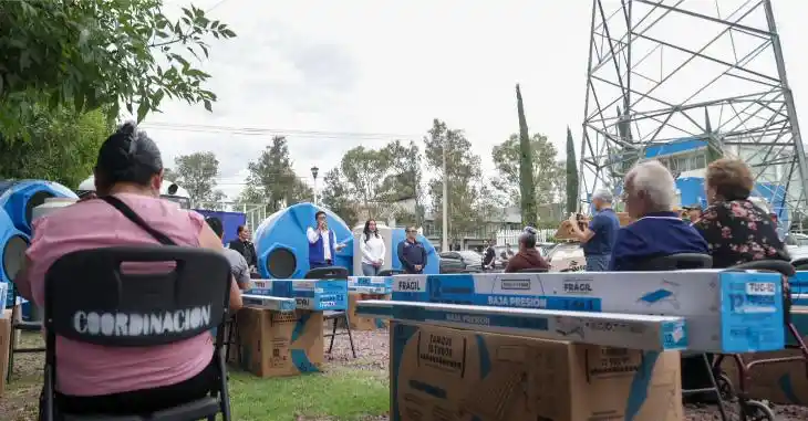 Una ciudadana sonríe junto a la caja que contiene un calentador solar de tubos de vacío. El modelo de subsidios busca facilitar el equipamiento básico de las viviendas y contribuir a la economía familiar.